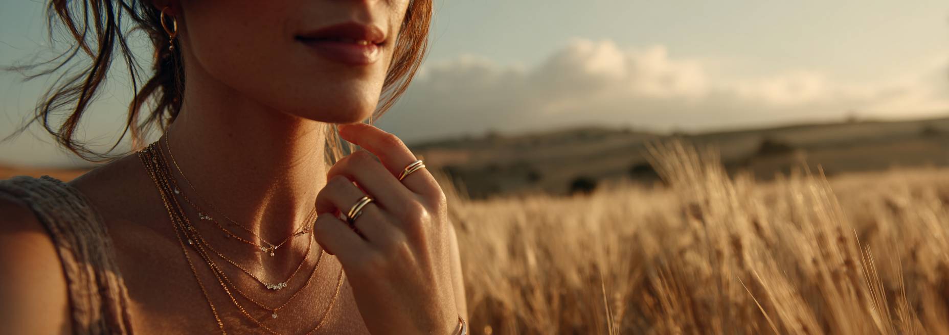Woman in a field with a necklace and ring, sunset or sunrise in the background
