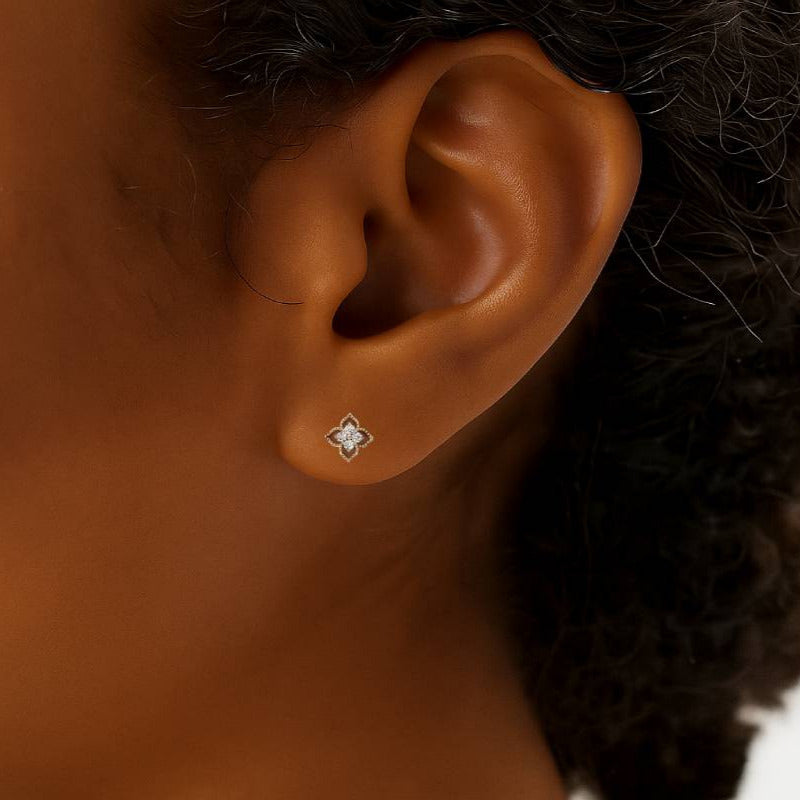 Close-up of an ear wearing a diamond stud earring with a blurred background