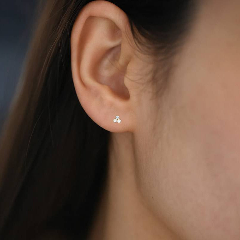 Close-up of an ear wearing a diamond stud earring with a blurred background