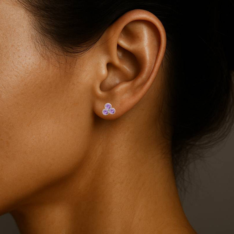 Close-up of a woman wearing a purple earring with a dark background
