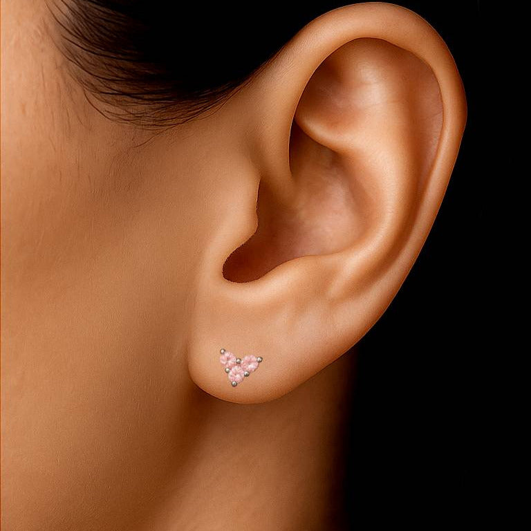 Close-up of an ear wearing a pink sapphire stud earring against a black background