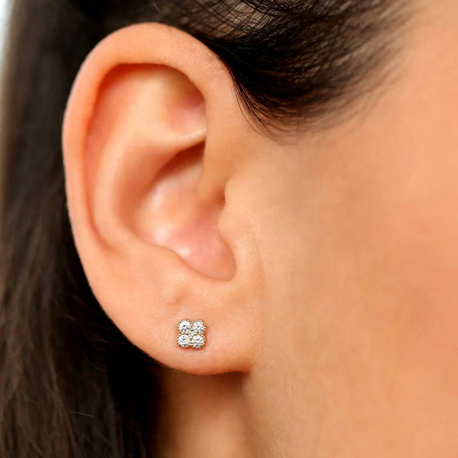 Close-up of an ear wearing a diamond stud earring with a blurred background