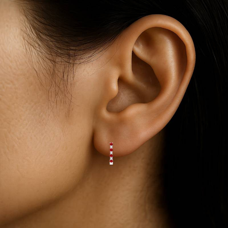 Close-up of an ear wearing a small earring with a dark background