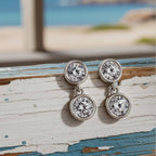 Gold earrings with clear gemstones on a wood background