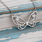 gold butterfly necklace with diamonds on a wood background