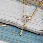 gold necklace with three round diamonds on wood background