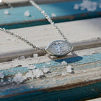 Gold necklace with a diamond pendant on a wood background