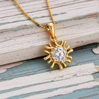 Gold sun-shaped pendant with a diamond on a wood background