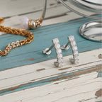 Gold hoop earrings with clear gemstones on a wood background