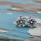 Pair of diamond stud earrings on a wood background