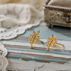leaf-shaped earrings on a wood background