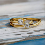 Gold ring with two diamonds on a wood background