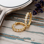 Gold hoop earrings with embedded diamonds on a wood background