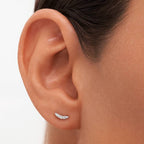 Close-up of an ear wearing a small silver earring against a neutral background