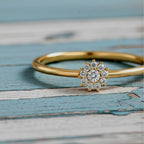 Gold ring with a diamond flower-shaped center on a wood background