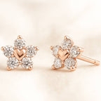 Rose gold earrings with heart and diamond details on a beige background
