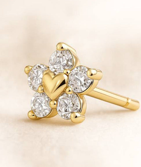 Gold earrings with heart and diamond design on a beige background