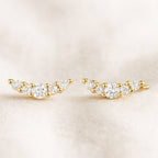 Pair of gold earrings with clear stones on a beige background