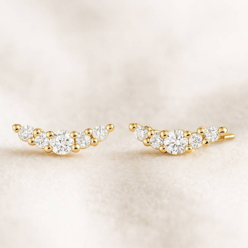 Pair of gold earrings with clear stones on a beige background