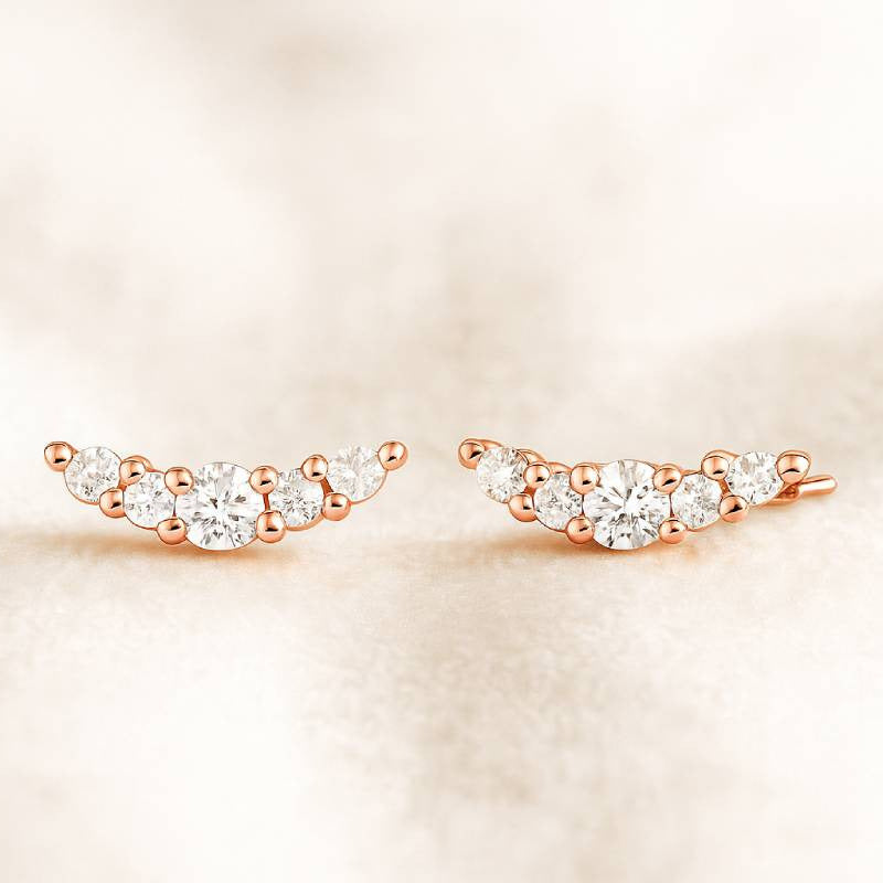 Rose gold earrings with clear gemstones on a soft beige background