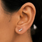 Close-up of an ear wearing a small silver earring with a blurred background