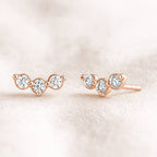 Rose gold earrings with clear gemstones on a soft beige background