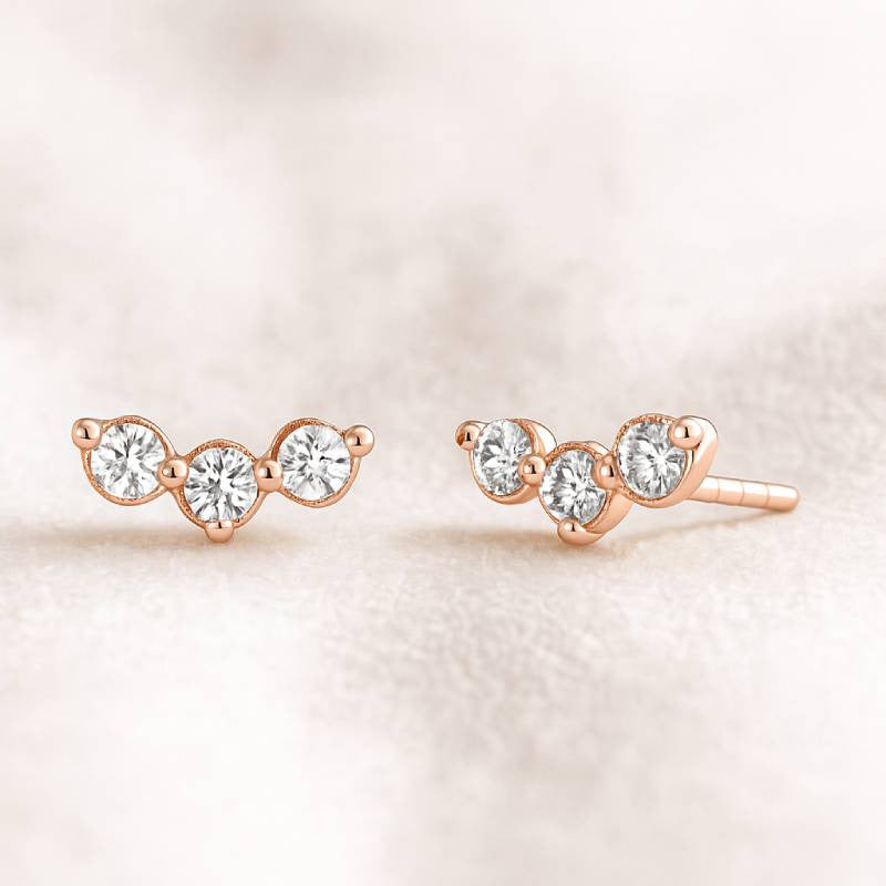 Rose gold earrings with clear gemstones on a soft beige background
