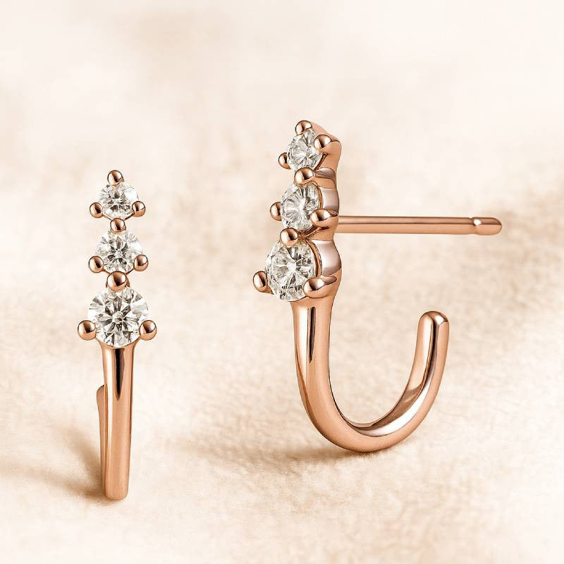 Rose gold earrings with clear gemstones on a beige background
