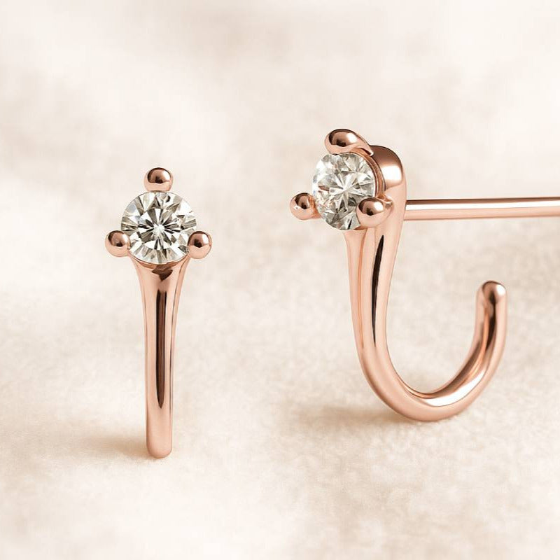 Rose gold earrings with clear gemstones on a beige background