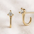 Gold earrings with clear gemstones on a light background