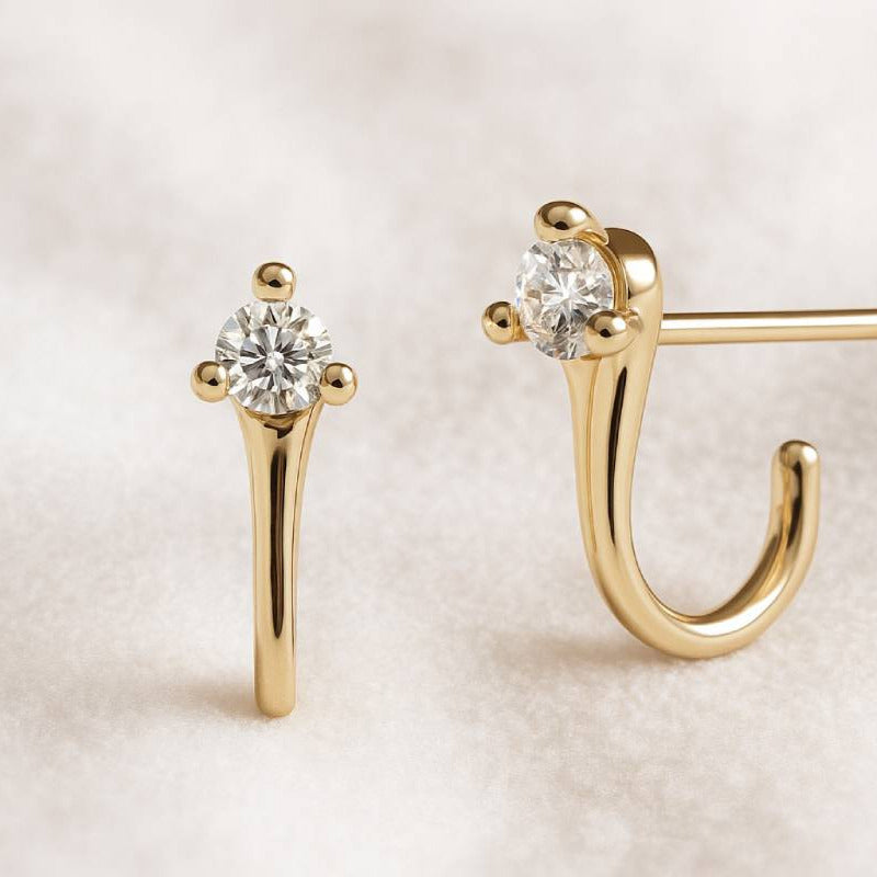 Gold earrings with clear gemstones on a light background