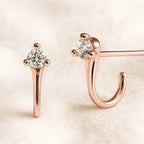 Rose gold earrings with clear gemstones on a beige background