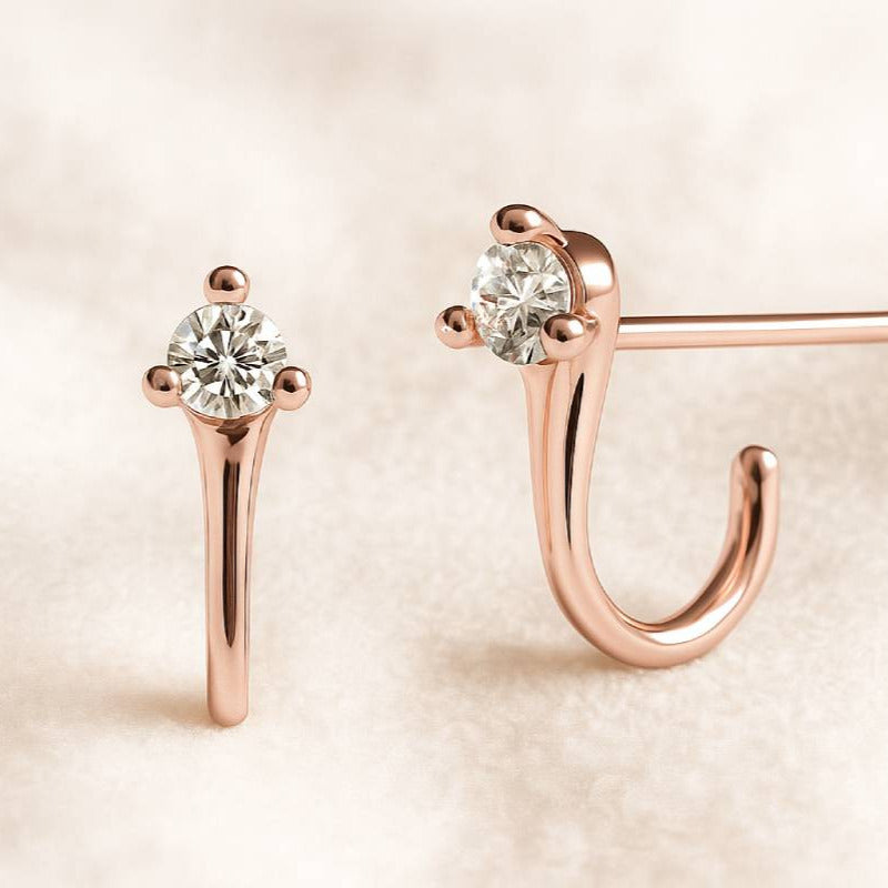 Rose gold earrings with clear gemstones on a beige background