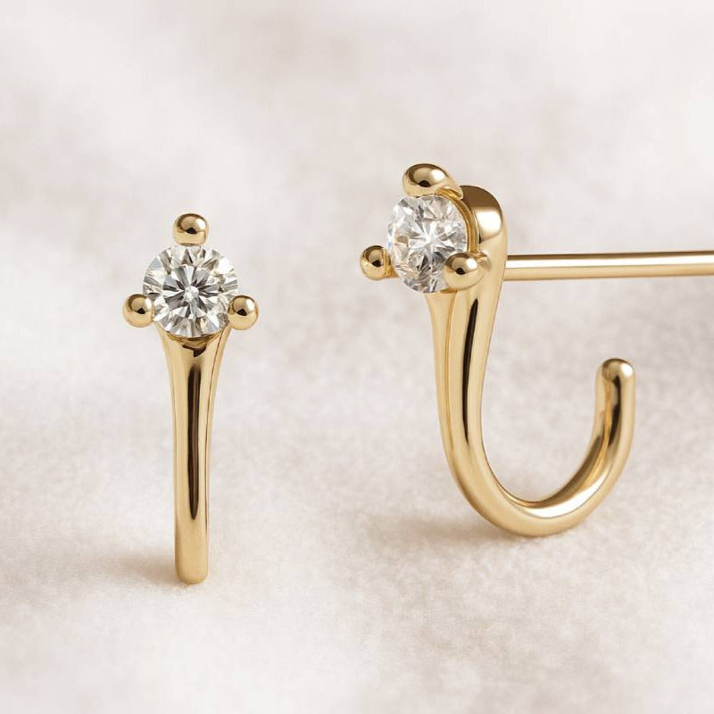 Gold earrings with clear gemstones on a light background