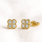 Gold earrings with diamond-like stones on a light background