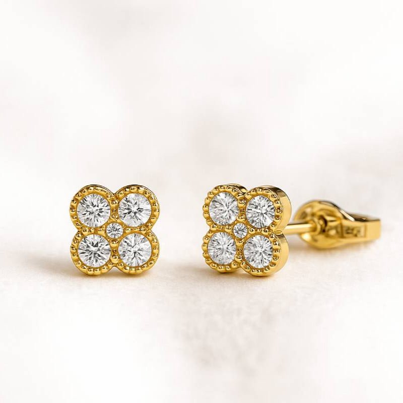 Gold earrings with diamond-like stones on a light background