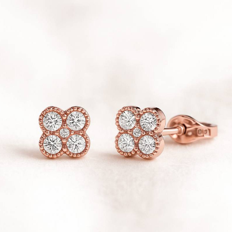 Rose gold earrings with diamond accents on a light pink background