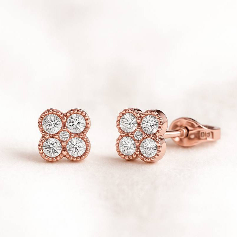 Rose gold earrings with diamond accents on a light pink background