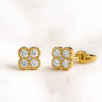 Gold earrings with diamond-like stones on a light background
