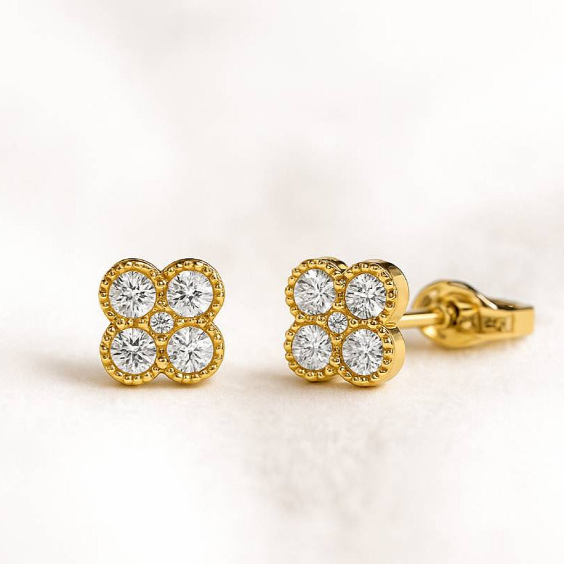Gold earrings with diamond-like stones on a light background