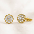Gold earrings with diamond-like stones on a light beige background
