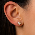 Close-up of an ear wearing a diamond stud earring with dark hair and skin background