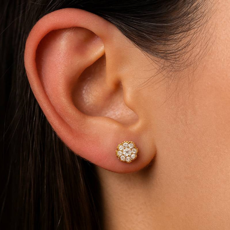 Close-up of an ear wearing a diamond stud earring with dark hair and skin background