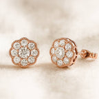 Rose gold earrings with diamond accents on a soft beige background