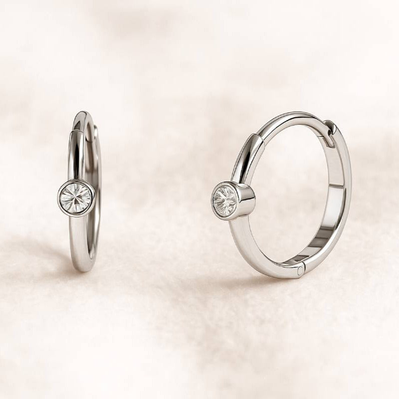 Pair of hoop earrings with small round gemstones on a light beige background