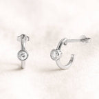 Pair of hoop earrings with round diamonds on a light pink background