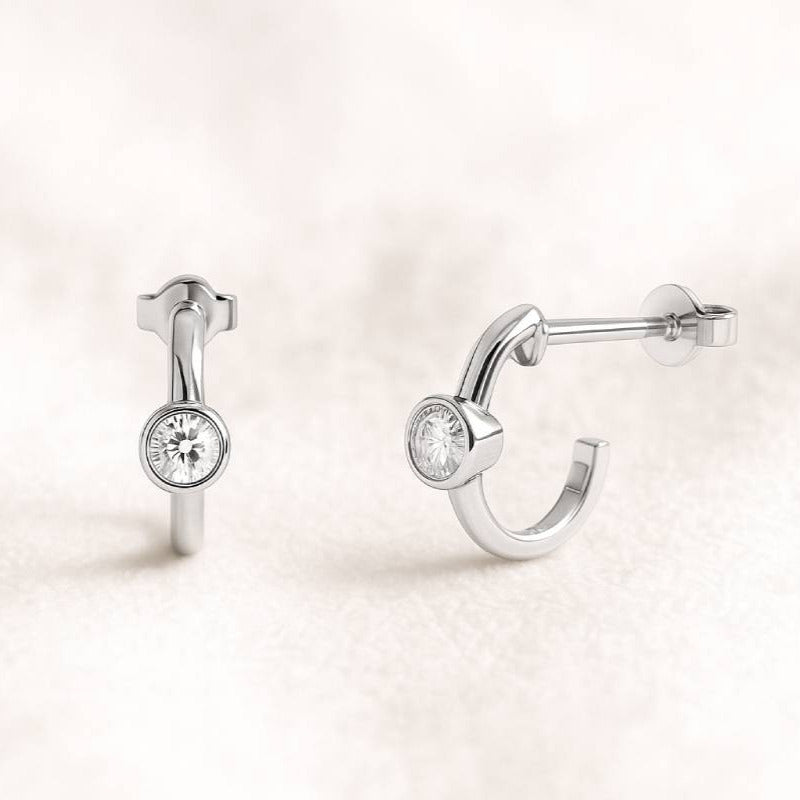 Pair of hoop earrings with round diamonds on a light pink background