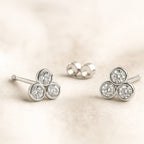 Pair of earrings with three circular gemstones on a beige background