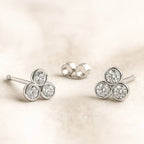 Pair of earrings with three circular gemstones on a beige background
