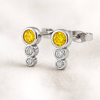 Gold cufflinks with yellow gemstones and small diamonds on a light background